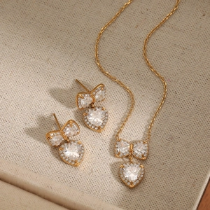 Golden stainless steel bow and heart necklace earring set with sparkling zircon crystals