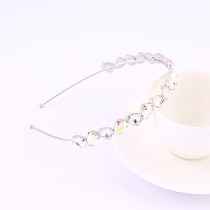 Close-up of a silver headband with teardrop crystals leaning on a white coffee cup