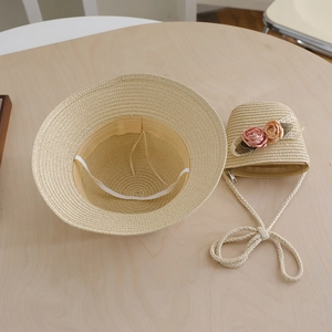 Detail view of straw sun hat and matching crossbody bag with floral accents and strap