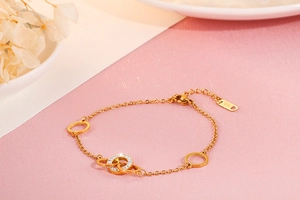 Detailed close-up of a 14K gold bracelet featuring a zircon-encrusted O-ring on a pink surface