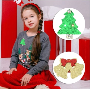 Detail of LED glowing Christmas tree and bell brooches with sequins for festive dress-up