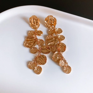 Gros plan de boucles d'oreilles franges en métal doré texturé sur une assiette en céramique