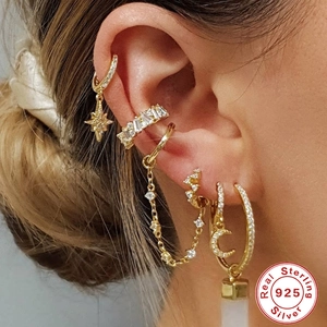 Close-up of gold S925 sterling silver earrings set with sparkling zircon on a model ear