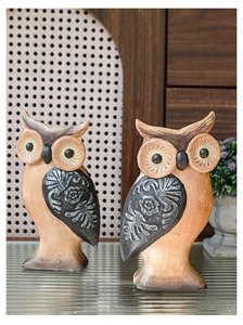 Dettaglio di due gufi decorativi rustici con ali floreali intagliate su vetro lucido