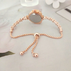 Detail of rose gold watch bracelet featuring a decorative link chain and adjustable slide buckle
