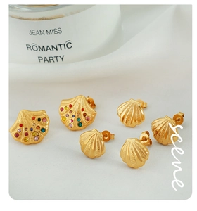 Detailed set of three golden shell earrings with sparkling rhinestones on white silk