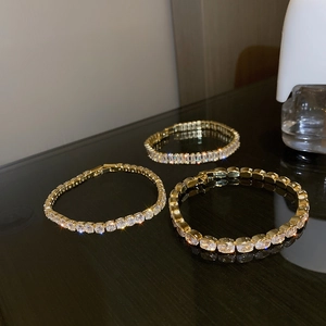 Elegant gold bracelet set with geometric zircon stones shown on a reflective black surface