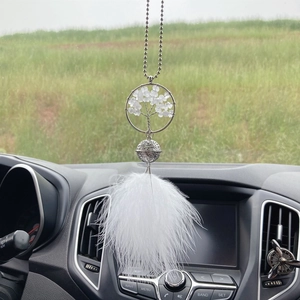 Macro detail of Tree of Life car ornament with silver metal chain and white feather
