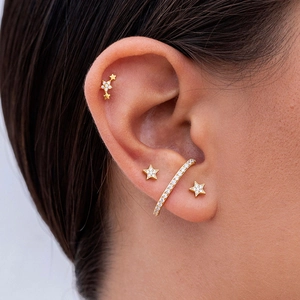 Close-up of gold star stud earrings and paved zircon ear cuff on ear for a stylish look