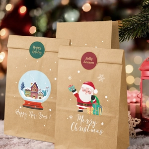 Brown kraft Christmas gift bag with Santa and snowflake motifs against a blurred festive background