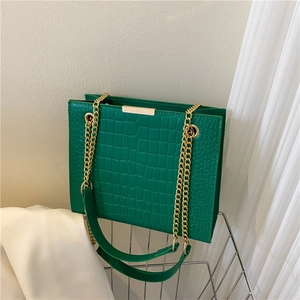 Chic green crocodile pattern tote bag with gold chain strap on a minimalist background