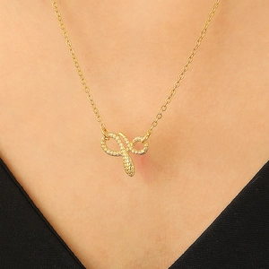 Close-up of golden snake pendant necklace worn on model with elegant black V-neck outfit