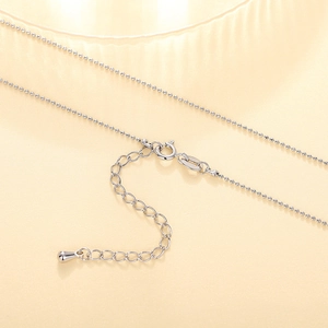 Macro detail of silver bead necklace showing secure spring clasp and extension chain
