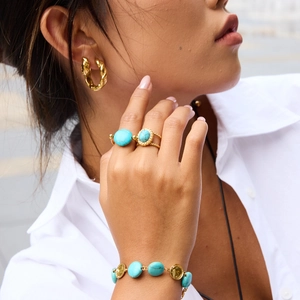 Close-up of gold turquoise jewelry set including rings, bracelet and twisted earrings