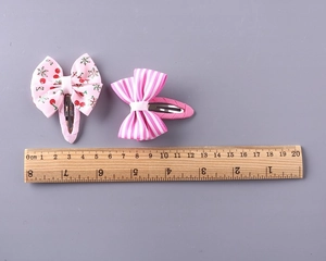 Close-up of girls' hair clips with pink cherry print and classic striped ribbon patterns