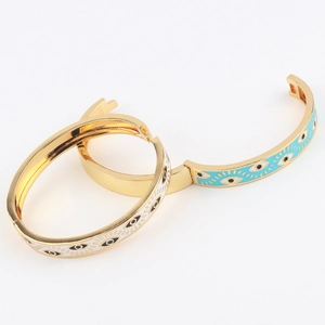 Detail of gold-plated evil eye bangles with white and turquoise enamel inlay work