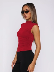 Close-up of red sleeveless top with mock neck and elegant side ruching detail