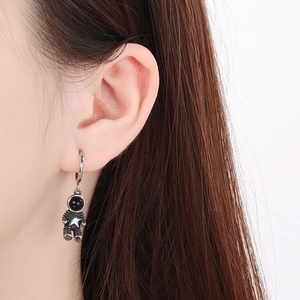 Close-up of a model wearing silver stainless steel astronaut-shaped hoop earrings