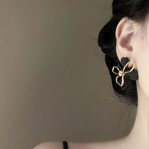 Detail showing double-layered hollow flower earrings worn on the ear for a luxury look