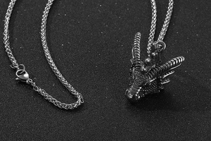 Macro d'un pendentif tête de dragon en acier inoxydable avec chaîne argentée sur fond noir