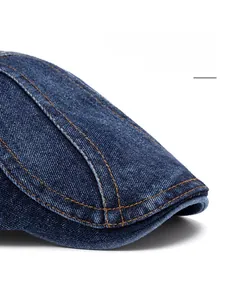 Detail of dark blue denim beret featuring widened foldable brim and orange stitching