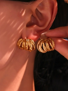 Close-up of chunky gold-plated C-shape earrings with layered spiral winding design