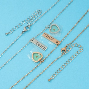 Detail of silver and rose gold faith necklaces with mustard seed heart pendants
