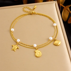 Detail of golden double-layer beach anklet with pearls, sea turtle and shell charms