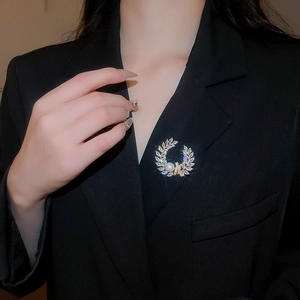 Macro detail of a laurel leaf brooch with 18k gold plating, pearl and zircon accents