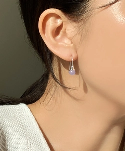 Detailed view of light purple bead drop earrings worn by a model in natural light