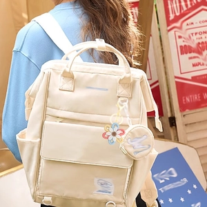 Beige nylon backpack featuring woven daisy flower keychain and small round coin purse