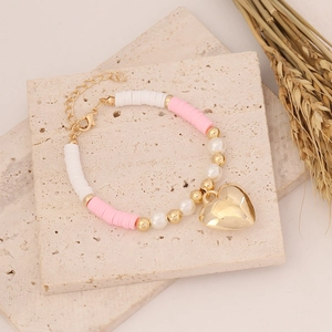Detail of pink and white clay bead bracelet with golden heart pendant and pearl accents
