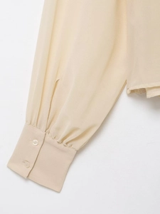 Detail shot of apricot chiffon blouse cuff with two matching buttons and fine stitching