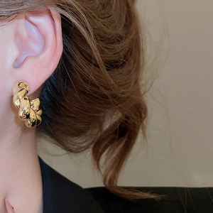 Close-up of golden chunky twisted rope hoop earrings on model with high gloss finish