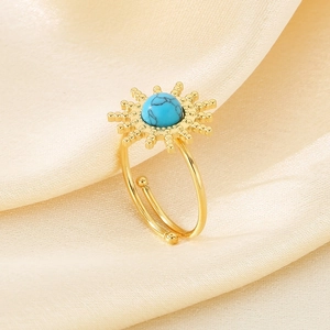 Macro shot of gold sunflower ring with turquoise inlay on champagne silk background