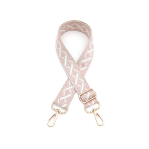 Détail de la bandoulière jacquard rose et blanc avec motifs géométriques et crochets dorés