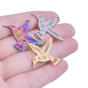 Detailed macro view of laser-cut hummingbird pendants in gold, silver, and rainbow finishes