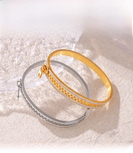 Detail of PVD plated zipper bangles in gold and silver finishes on modern acrylic display