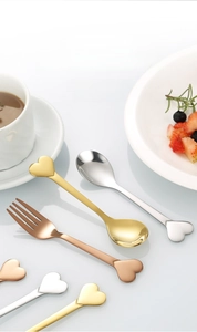 Close-up of heart-shaped stainless steel dessert spoon and fork set in rose gold finish