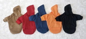 Flat lay view of five solid color fleece dog hoodies in various colors on white fur