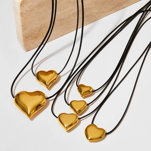 Minimalist gold heart pendant necklaces with black wax cord on a marble display