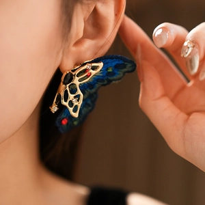 Vue détaillée de boucles d'oreilles papillon vintage avec broderie bleue et accents dorés
