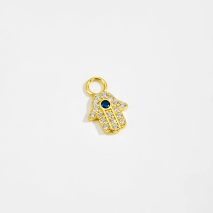 Macro shot of gold Hamsa pendant with sparkling zircon and deep blue crystal