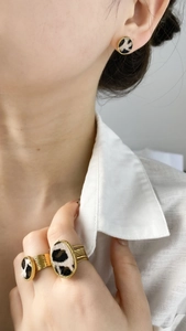 Close-up of leopard print jewelry set with gold ring and matching stud earrings