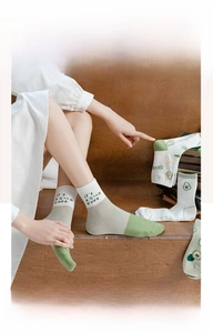Detail of green mid-calf cotton socks with cute avocado embroidery and soft texture