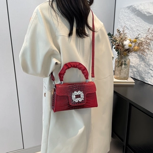 Red crocodile texture handbag with crystal buckle shown on model in a minimalist setting