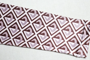 Detailed close-up of geometric pattern print and stitching on a brown long-sleeve jumpsuit