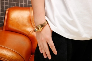 Detailed close-up of a gold-plated lion head charm on a braided bracelet for men