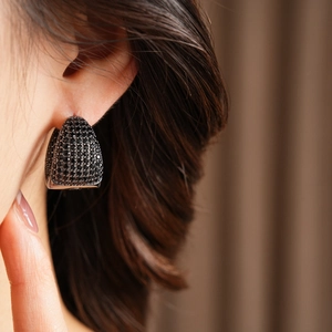 Close-up of black zircon pave-set C-shaped hoop earring on model earlobe