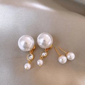 Macro shot of pearl and rhinestone tassel earrings on elegant silk textured background
